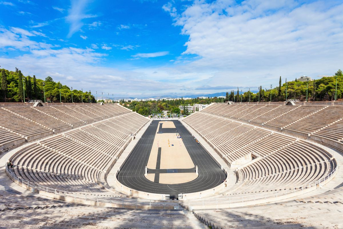 Panathenaic Stadium with marble seating surrounding a long track under a bright sky.